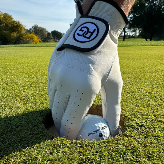 A golfer wearing the Phoenix Signature Cabretta leather glove picking a Phoenix Pro Elite 5-piece golf ball out of the cup.